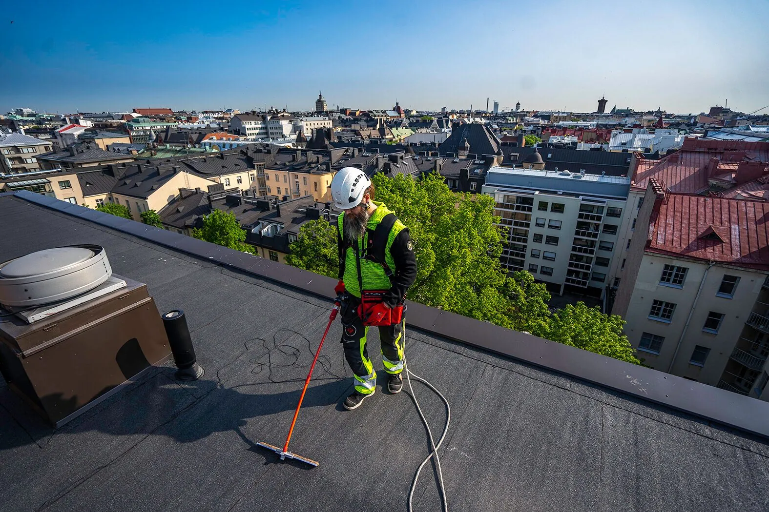 Asentaja tekee ELD-vuotokartoitusta kaupunkikerrostalon bitumikatolla